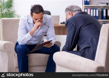 The old man visiting young male doctor psychologist. Old man visiting young male doctor psychologist