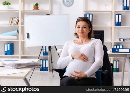 The old pregnant woman working in the office. Old pregnant woman working in the office