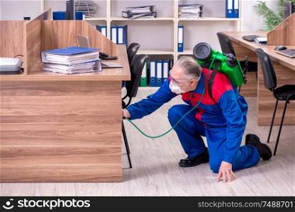 The old professional contractor doing pest control in the office . Old professional contractor doing pest control in the office
