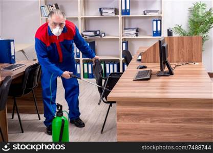 The old professional contractor doing pest control in the office . Old professional contractor doing pest control in the office