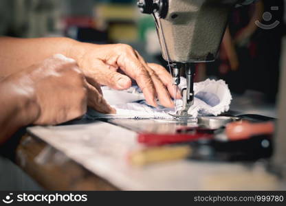The old woman's hand is using a sewing machine.