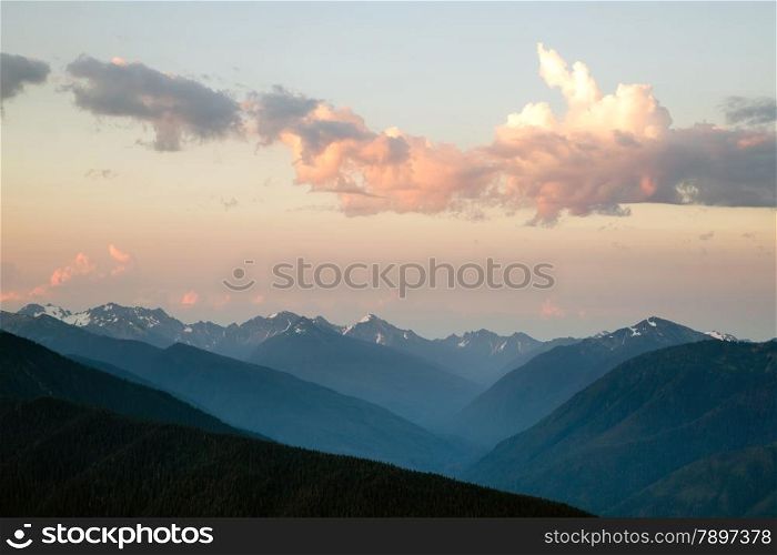 The Olumpic Mountains stand against a dramatic sky at sunrise