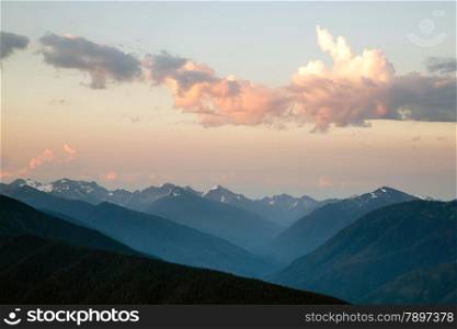 The Olumpic Mountains stand against a dramatic sky at sunrise