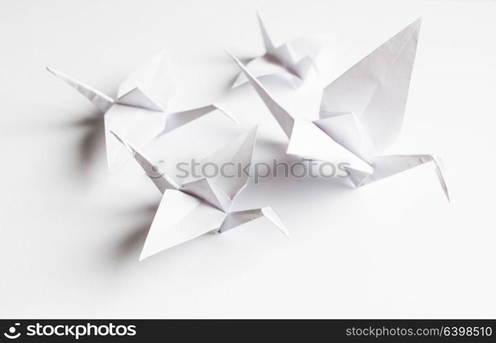 The origami crane is made of white paper, isolated on a white background. White crane handmade