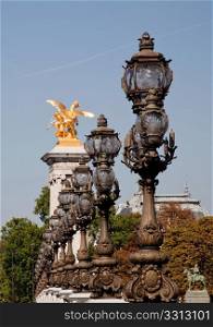 The ornate lampposts on the Pont Alexandre III lead towards one of the golden statues on the bridge