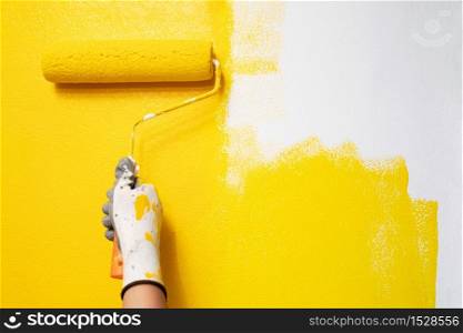 The painter is painting the yellow wall room.