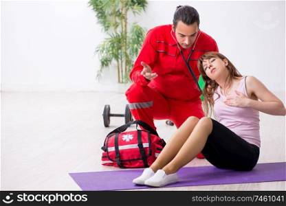The paramedic in red visiting young woman in gym . Paramedic in red visiting young woman in gym 