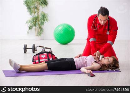 The paramedic in red visiting young woman in gym. Paramedic in red visiting young woman in gym