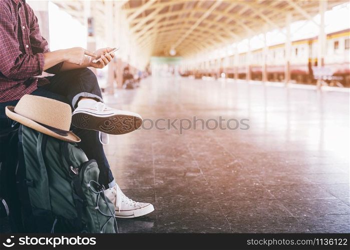 The passengers are waiting for the Station platform. Young man traveler with backpack and hat looking read the map with waiting for train. the tourist travel concept.