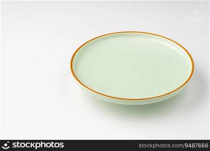 The pastel green ceramic plate with orange outlines on a white background. Pastel green ceramic plate with orange outlines