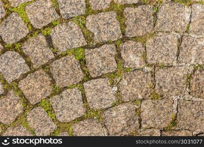 The pavement of granite stone. Paved roadway street. any paved a. The pavement of granite stone. Paved roadway street. any paved area or surface. Old cobblestone road pavement texture, grass between stones.