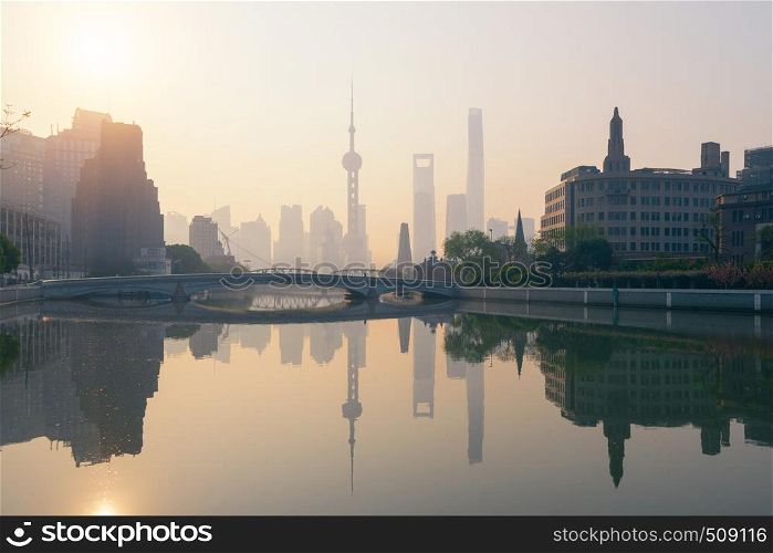 The Pearl in Shanghai Downtown skyline by Huangpu River with fog, China. Financial district and business centers in smart city in Asia. Skyscraper and high-rise buildings near The Bund at sunrise.