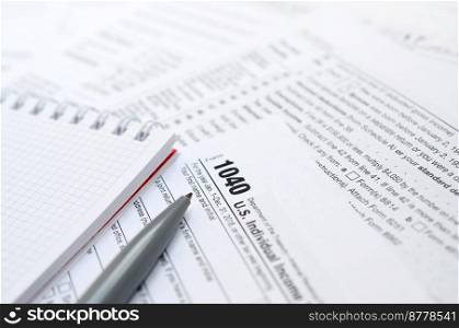The pen and notebook is lies on the tax form 1040 U.S. Individual Income Tax Return. The time to pay taxes