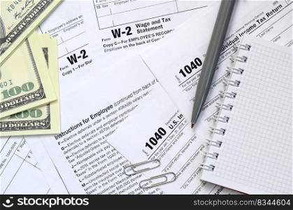 The pen, notebook and dollar bills is lies on the tax form 1040 U.S. Individual Income Tax Return. The time to pay taxes