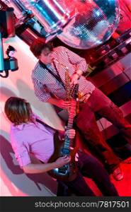 The performance of a saxophonist and a guitarist in a nightclub.