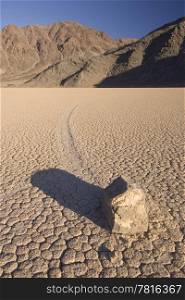The phenomenon of the moving rocks at Death Valley Race Track Playa. The setting sun casts a shadow over the near by rock, still basking the mountains in the background in a warm glow. Death Valley 2006