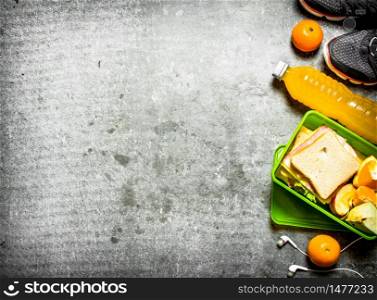 The picnic set. Sandwiches, orange juice and fruit. On the stone table. Sandwiches, orange juice and fruit. On the stone table