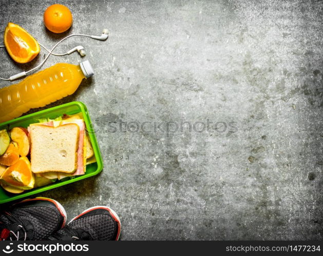 The picnic set. Sandwiches, orange juice and fruit. On the stone table. Sandwiches, orange juice and fruit. On the stone table