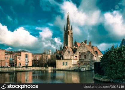 The picturesque city landscape with a lake, Old St Johns Hospital and the Church of Our Lady in Bruges, Belgium. Toning in cool tones