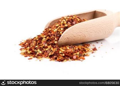 The pile of a crushed red pepper, dried chili flakes and seeds isolated on white background in a scoop