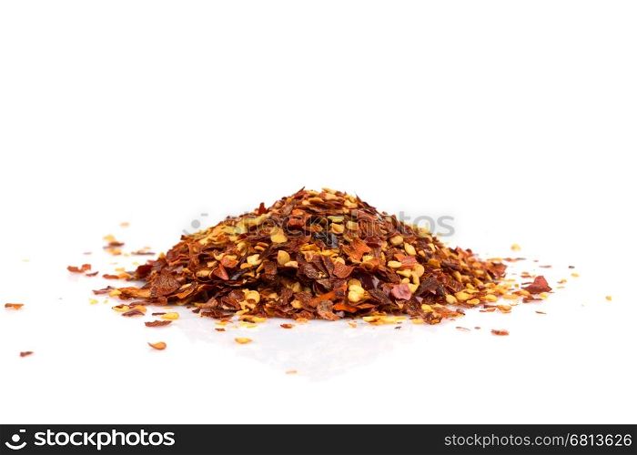 The pile of a crushed red pepper, dried chili flakes and seeds isolated on white background