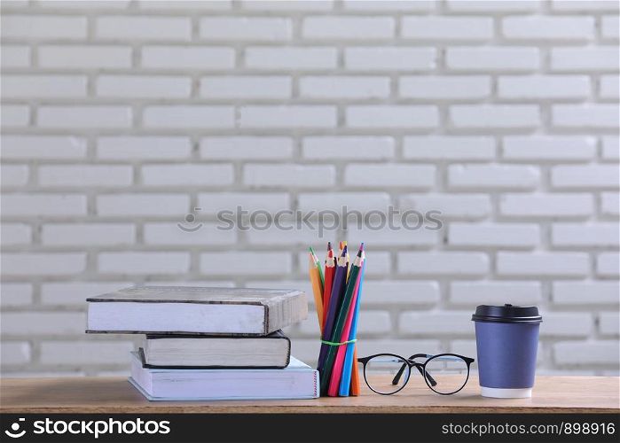the pile of books, paper and pencil on the desk