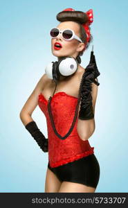 The pin-up photo of a cute girl in sunglasses with unplugged music headphones.