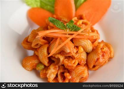 The pipe rigate italian pasta with tomato sauce and egg, chili and fresh carrot slice in white plate, copy space 