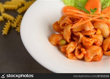 The pipe rigate italian pasta with tomato sauce and egg, chili and fresh carrot slice in white plate, copy space 