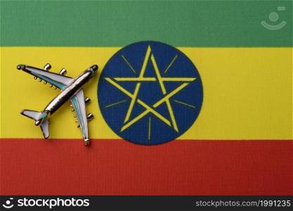The plane over the flag of Ethiopia, the concept of travel. Toy airplane on the flag as a background.. The plane over the flag of Ethiopia, the concept of travel.