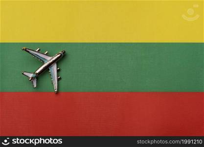 The plane over the flag of Lithuania, the concept of travel. Toy plane on the flag as a background.. The plane over the flag of Lithuania, the concept of travel.