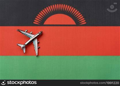 The plane over the flag of Malawi, the concept of travel. Toy plane on the flag as a background.. The plane over the flag of Malawi, the concept of travel.
