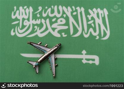 The plane over the flag of Saudi Arabia, the concept of travel. Toy plane on the flag as a background.. The plane over the flag of Saudi Arabia, the concept of travel.