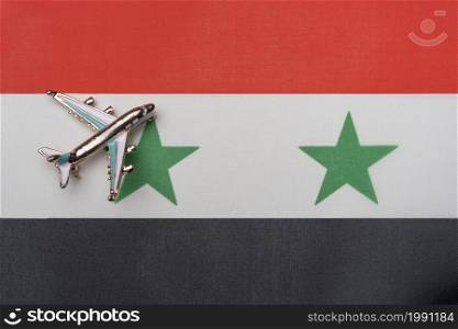 The plane over the flag of Syria, the concept of travel. Toy plane on the flag as a background.. The plane over the flag of Syria, the concept of travel.