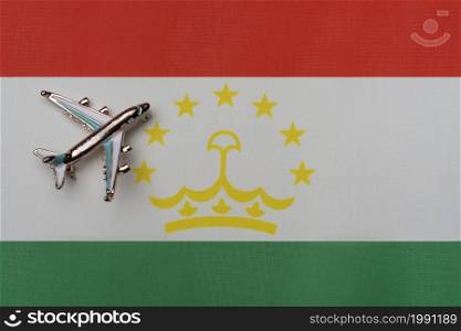 The plane over the flag of Tajikistan, the concept of travel. Toy plane on the flag as a background.. The plane over the flag of Tajikistan, the concept of travel.