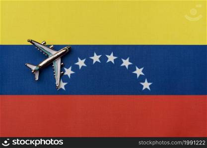 The plane over the flag of Venezuela, the concept of travel. Toy plane on the flag as a background.. The plane over the flag of Venezuela, the concept of travel.