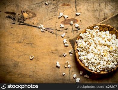The popcorn in the bowl. On a wooden table.. The popcorn in the bowl.
