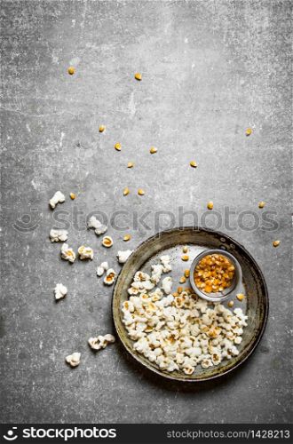 The popcorn with corn in a old pan. On the Stone table.. The popcorn with corn in a old pan.