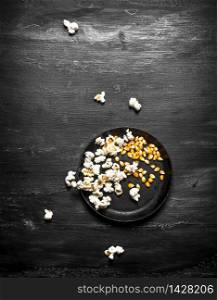 The popcorn with corn in dish. On the black wooden table.. The popcorn with corn in dish.
