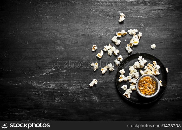 The popcorn with corn in dish. On the black wooden table.. The popcorn with corn in dish.