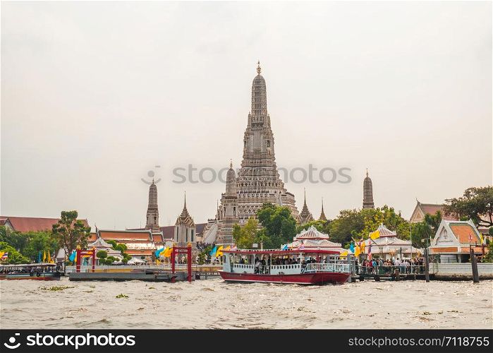 The Prangs of Wat Arun temple alongside the Chao Phraya River. Bangkok, Thailand. English translation from Thai language : The memorial waterfront of Mrs. Peuak.