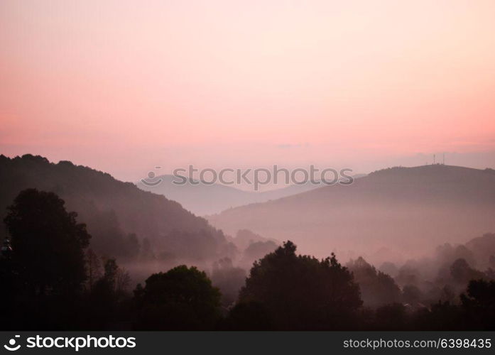 The predawn hour in mointans. View from the peak on the village. Morning fog in moutnains