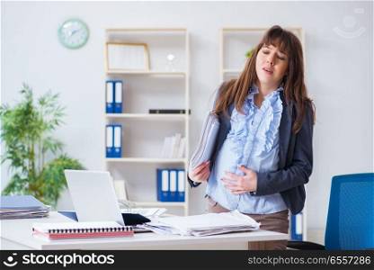 The pregnant woman struggling to do work in office. Pregnant woman struggling to do work in office. The pregnant woman struggling to do work in office
