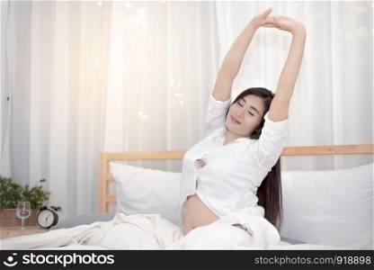 The pregnant woman waking up and stretching in the morning, Family concept, Beauty concept
