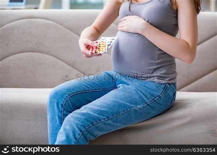 The pregnant woman with a belly tummy sitting on a sofa at home. Pregnant woman with a belly tummy sitting on a sofa at home