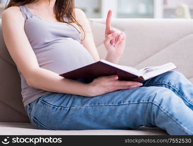 The pregnant woman with a belly tummy sitting on a sofa at home. Pregnant woman with a belly tummy sitting on a sofa at home