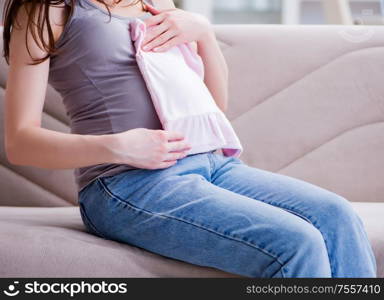 The pregnant woman with a belly tummy sitting on a sofa at home. Pregnant woman with a belly tummy sitting on a sofa at home