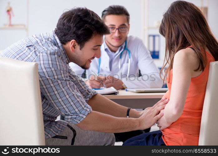 The pregnant woman with her husband visiting the doctor in clinic. Pregnant woman with her husband visiting the doctor in clinic