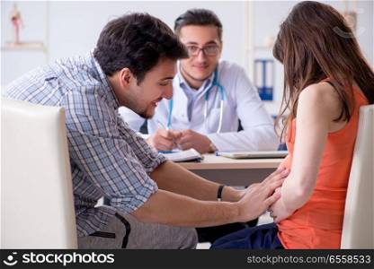 The pregnant woman with her husband visiting the doctor in clinic. Pregnant woman with her husband visiting the doctor in clinic
