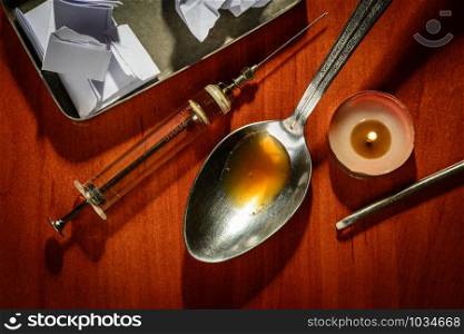 The preparation of heroine with a spoon, a syringe and a candle on a table
